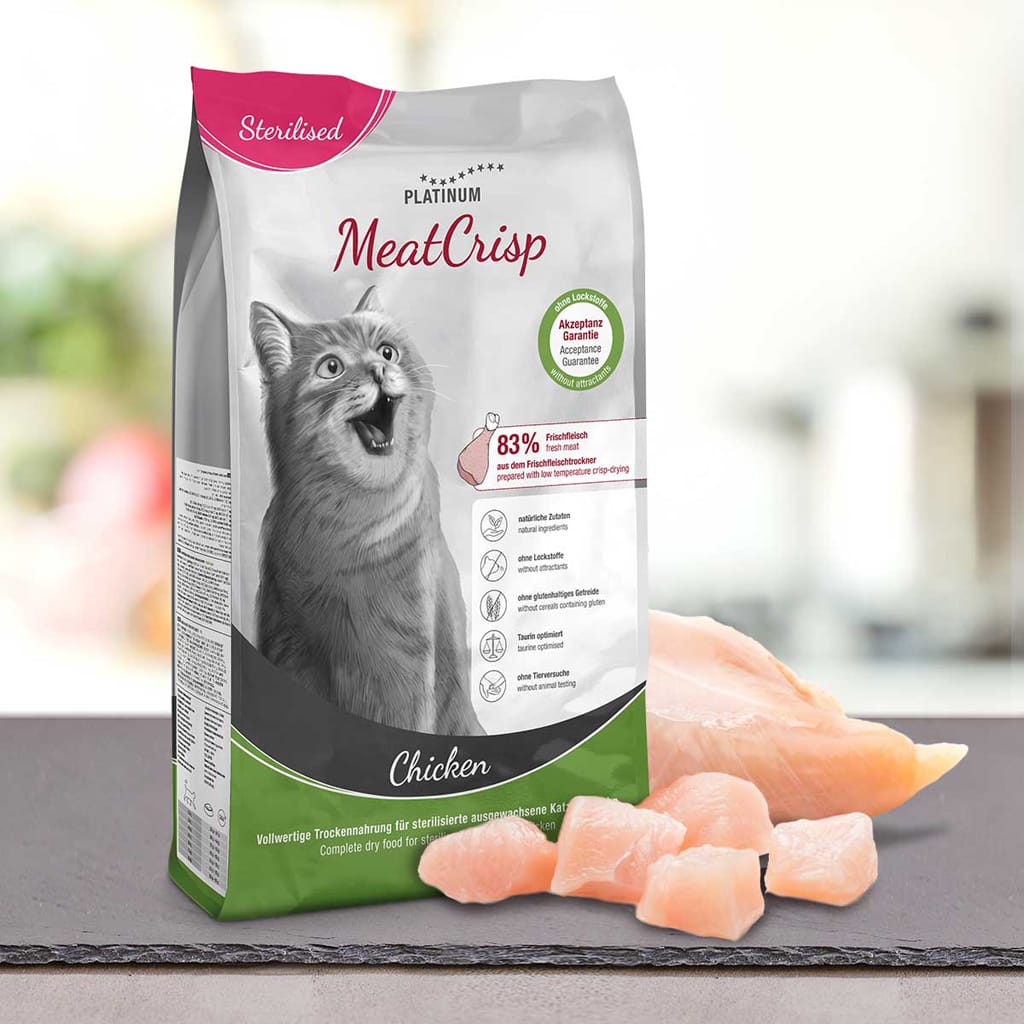 Vrečka PLATINUM MeatCrisp Sterilised Chicken suha hrana za mačke z oznako za sterilizirane mačke stoji za koščki piščančjega mesa z veselo sivo mačko na embalaži.